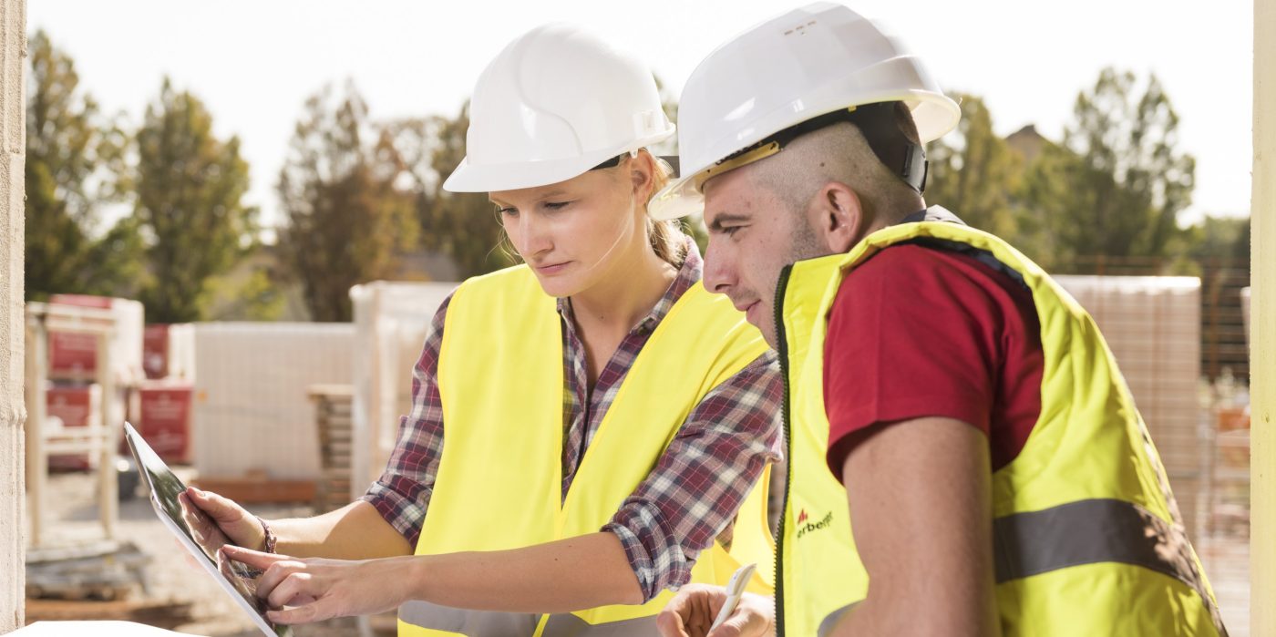 Woman pointing at tablet with male coworker taking notes at construction site, Fast Forward Commercial Excellence