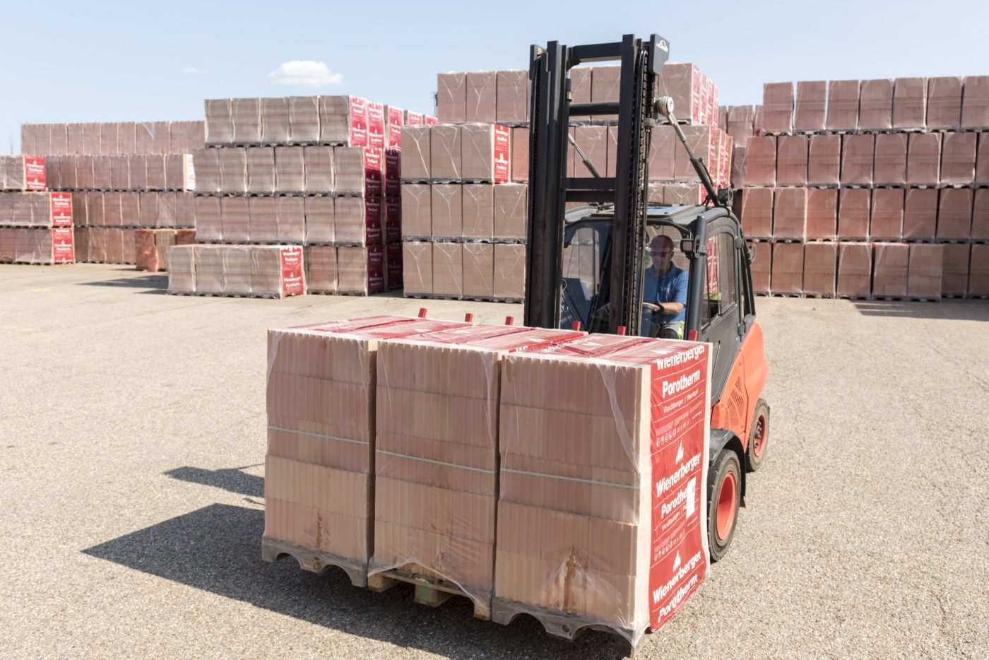 Forklift loads clay block pallets on tuck on stockyard