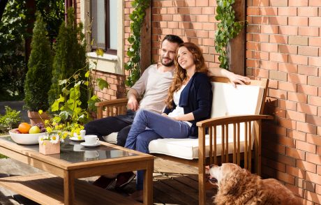 Man and woman sitting on garden bench in front of brick-lined façade