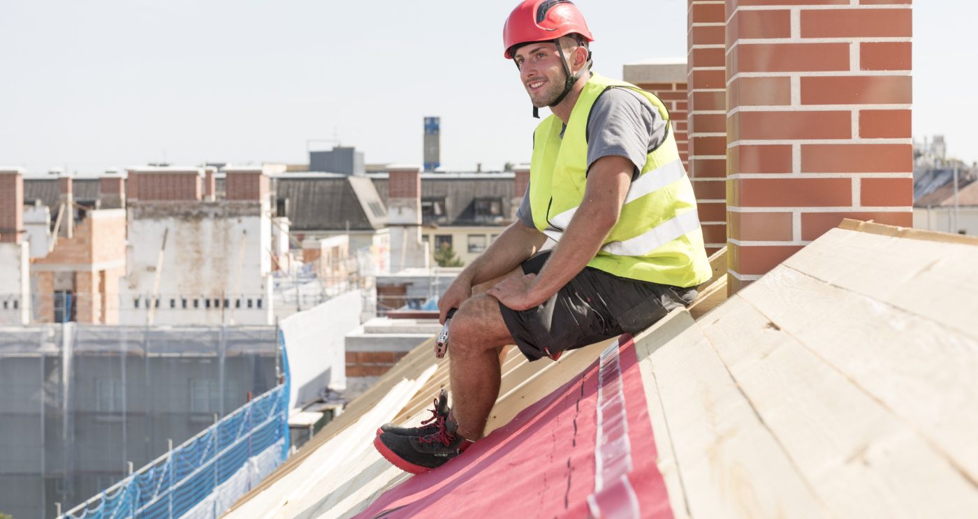 Smiling roofer sitting on roof