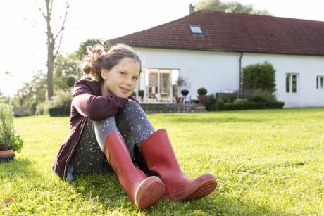 Girl sitting in the grass single family house in the background