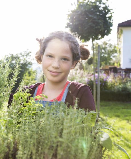 Girl with fresh herbs in garden facing camera