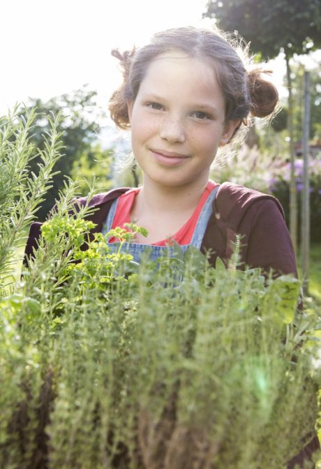 Girl with fresh herbs in garden facing camera