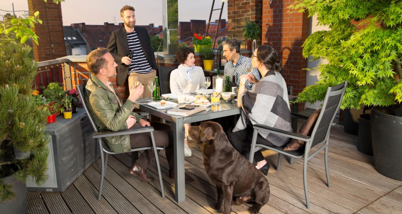 Friends sitting together on rooftop terrace with city view in evening light