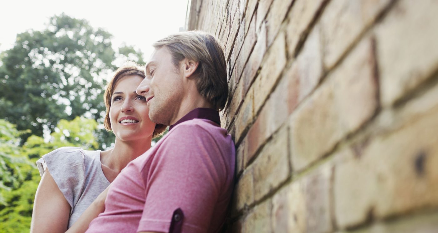 Young loving couple leaning against brick façade