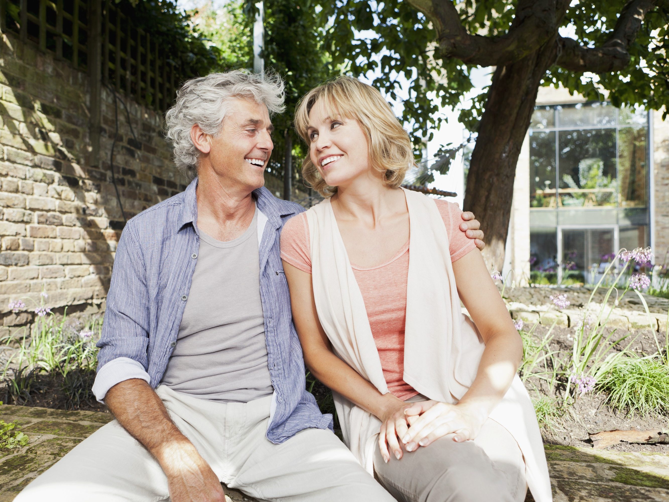 Smiling best-ager couple sitting in back yard