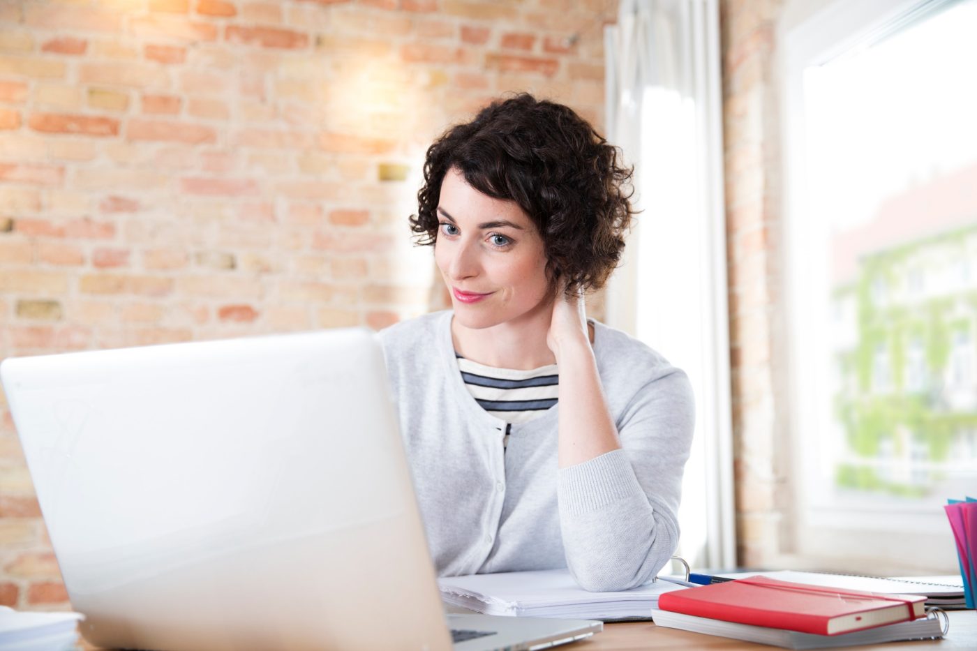 Woman looking at computer screen in front of brick-lined wall