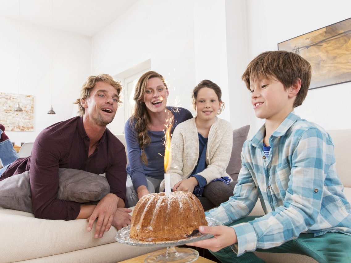 Boy carrying birthday cake with sparkler