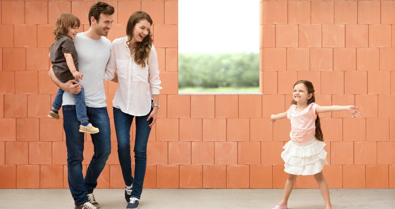 Parents watching girl in joy over her future room in building shell