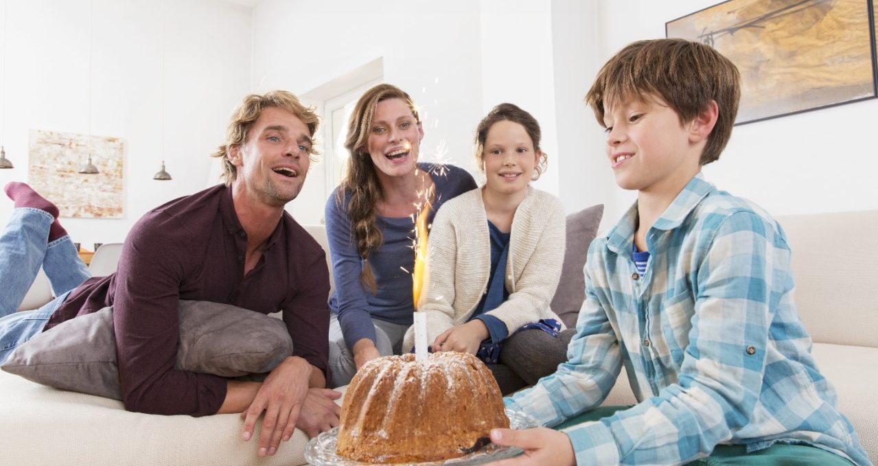 Boy carrying birthday cake with sparkler